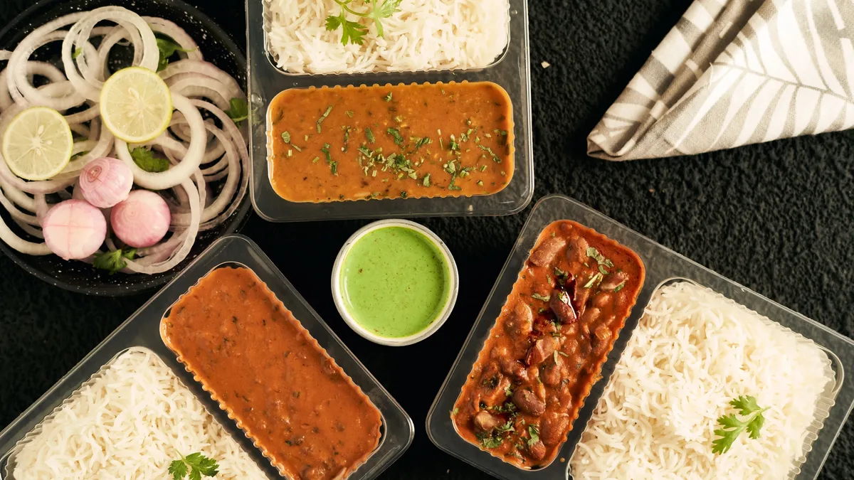 A collection of Indian food dishes, including rice, curry, and salad, arranged on a black surface.